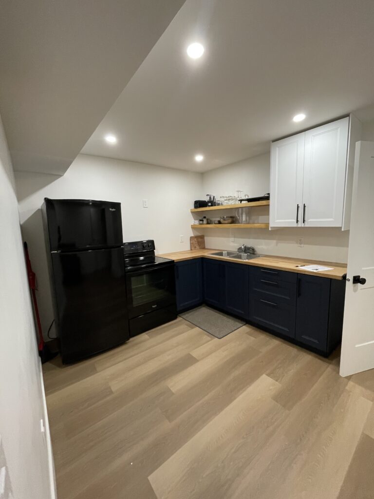 A newly renovated basement show a legal rental suite with floating shelves, large countertops, and a fully functional kitchen.