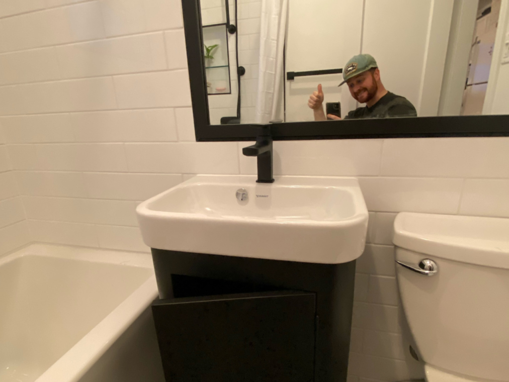 A mirror selfie of Isaac Bowden giving a thumbs up in the mirror of the newly renovated bathroom.