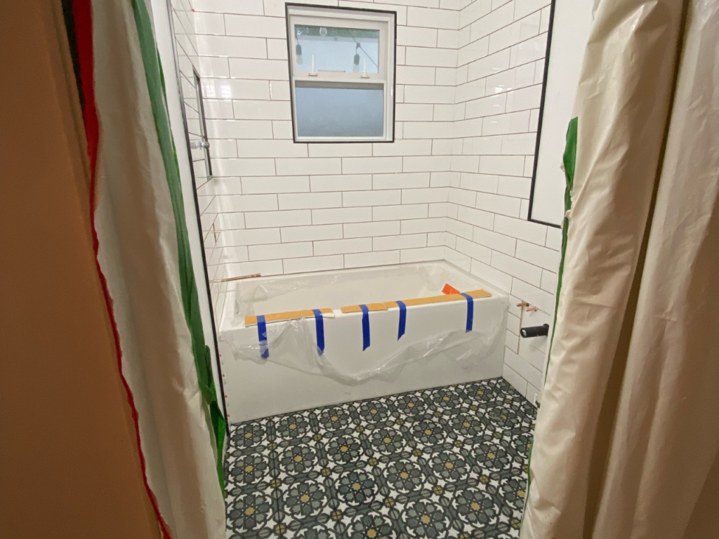 White tiles surround a bathtub in an in-progress bathroom renovation.