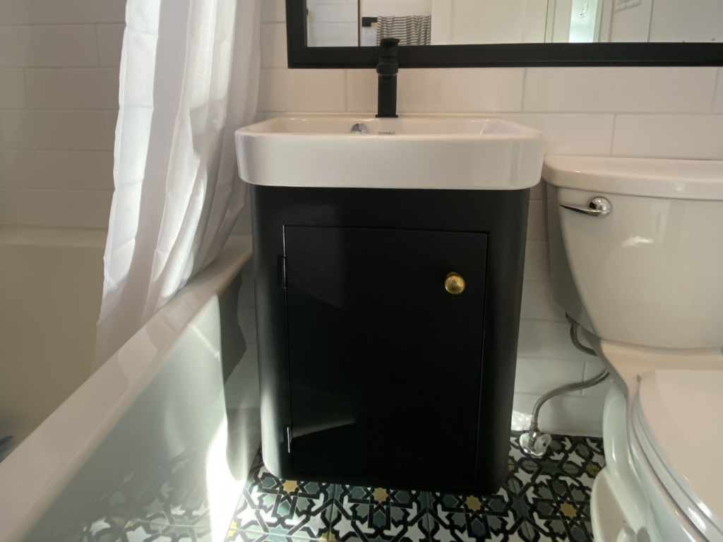A black cabinet and built-in sink sit in between the bathtub and toilet to maximize space.